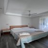 Camera con letto matrimoniale, lenzuola a righe, ventilatore e finestra con tende bianche.