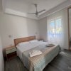 Una camera da letto bianca con letto matrimoniale e due comodini, ventilatore a soffitto e specchio.