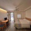 Una camera con letto matrimoniale, scrivania, sedie, TV e accesso esterno, decorata con toni neutri.