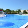Piscina con fontana a fungo, palme e edificio sullo sfondo.