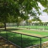 Un campo da bocce verde all'aperto, circondato da alberi e recinzione.