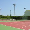 Campo da tennis all'aperto con recinzione, sedie bianche e luci.