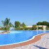 Una grande piscina con fontane circondata da lettini e piante sotto un cielo limpido.