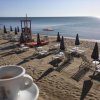 Vista sulla spiaggia con ombrelloni chiusi e tazzina di caffè in primo piano.