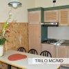Cucina con tavolo, fiori e armadietti in legno chiaro.