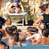 Persone in piscina seguono istruzioni di due istruttrici.