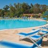 Piscina all'aperto con lettini blu e palme.