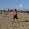 Persone giocano a beach volley su una spiaggia soleggiata.