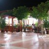 Terrazza di ristorante all'aperto di notte, con tavoli tra alberi illuminati.