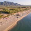 Spiaggia sabbiosa con mare e montagne sullo sfondo.