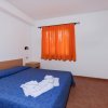 Stanza con letto matrimoniale, copriletto blu e tenda arancione.