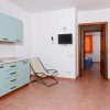 Cucina a lato, due letti a castello, TV a parete.