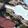 Piscina a forma di chitarra circondata da ombrelloni e lettini.