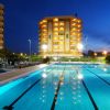 Edificio illuminato di notte con piscina in primo piano.