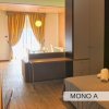 Monolocale moderno con letto, tavolo, e tende aperte verso un balcone.