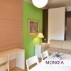 Soggiorno con tavolo da pranzo, parete verde, lampada e decorazioni floreali.