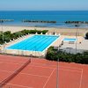 Piscina all'aperto vicino a un campo da tennis e la spiaggia.