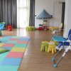 Sala giochi per bambini con tappetone colorato e sedie piccole.