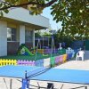 Un tavolo da ping pong vicino a un'area giochi per bambini recintata.