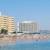 Una spiaggia affollata con edifici alti sullo sfondo e persone che nuotano nel mare.