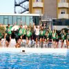 Un gruppo di persone salta nel bordo di una piscina, esultando gioiosamente.