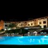 Piscina illuminata di notte, circondata da edifici.