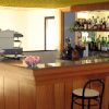 Bancone bar in legno con sgabelli e bottiglie.