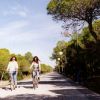 Due persone in bici su un sentiero alberato.