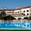 Edificio con piscina e sedie bianche in primo piano.