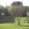 Parco giochi con altalene e scivolo su un prato verde.