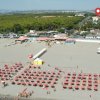 Vista aerea di una spiaggia con ombrelloni rossi.