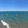 Vista panoramica del mare con bagnanti e kayak.