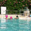 Piscina all'aperto con persone e cappelli colorati.