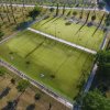 Campo da calcio e tennis su erba, visto dall'alto con alberi attorno.