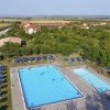 Due piscine all'aperto circondate da alberi e ombrelloni blu, vista dall'alto.