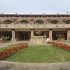 Un edificio con archi e fiori rossi in un giardino curato.