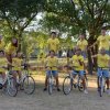 Ragazzi in magliette gialle posano su biciclette in un parco.