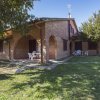 Casa in mattoni con archi, sedie bianche all'aperto e un prato verde.