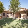 Casa in mattoni con archi, vasi e alberi in un giardino.