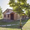 Edificio in mattoni con tetto spiovente, circondato da alberi e un giardino curato.