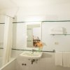 Bagno con vasca, specchio, asciugamani e fiori sul lavandino.
