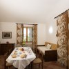 Sala da pranzo con tavolo apparecchiato, scale in legno e tende con motivo floreale.