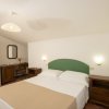 Camera da letto con letto matrimoniale, comodini e scrivania con sedia in legno.