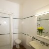 Bagno con doccia, lavandino, specchio e asciugamani bianchi.