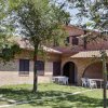 Una casa in mattoni circondata da alberi, con sedie bianche sotto il portico.