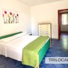 Camera con letto matrimoniale, coperta verde, pavimento blu e un dipinto di tulipani.