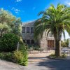 Edificio in pietra con palme e tavolini all'aperto.