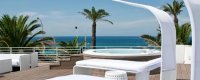 Una terrazza con vista sull'oceano, lettini bianchi e palme.