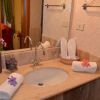 Bagno con lavandino in marmo, asciugamani e decorazioni floreali su specchio.