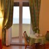Tavolino con teiera e tazze vicino a una finestra, tenda verde e vista mare.